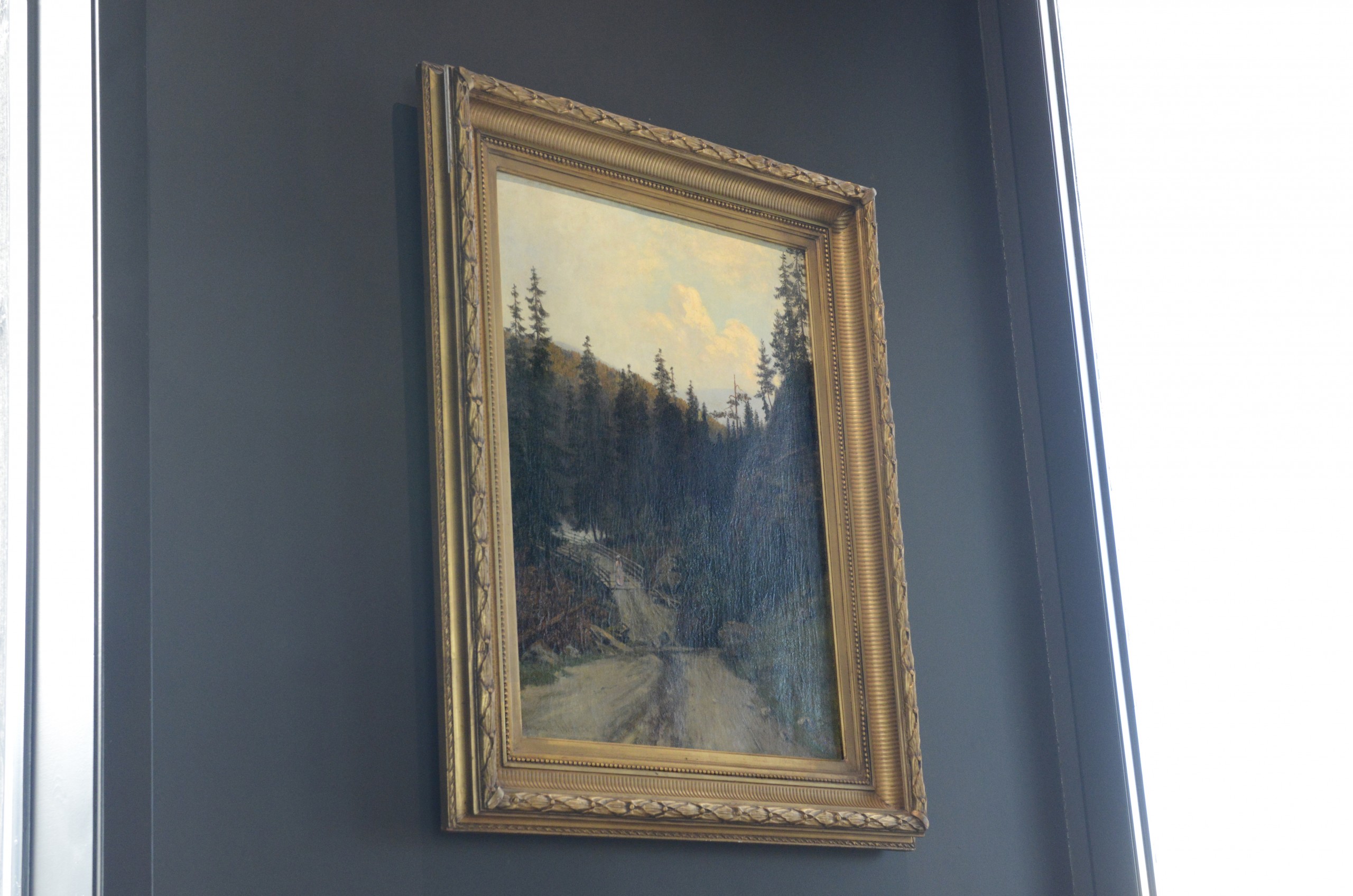 "Kvinne med parasoll på landevei" Olje på lerret 92 x 66 cm Dette motivet er trolig fra Modum Bad. Herman Anker anses som den norske bjørkeskogens maler, og han utførte et stort antall flotte malerier med motiver som dette.